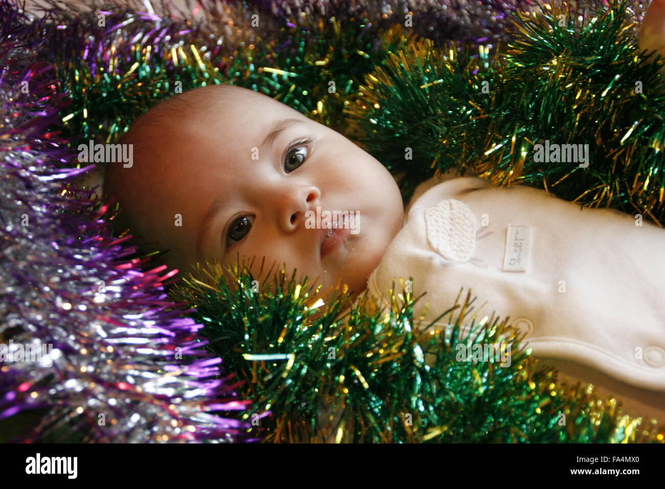 Très peu cute girl lying in bed with a Christmas garland Banque D'Images