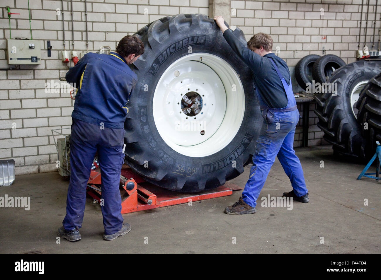 Apprenti ajusteur changer un pneu du tracteur. Banque D'Images