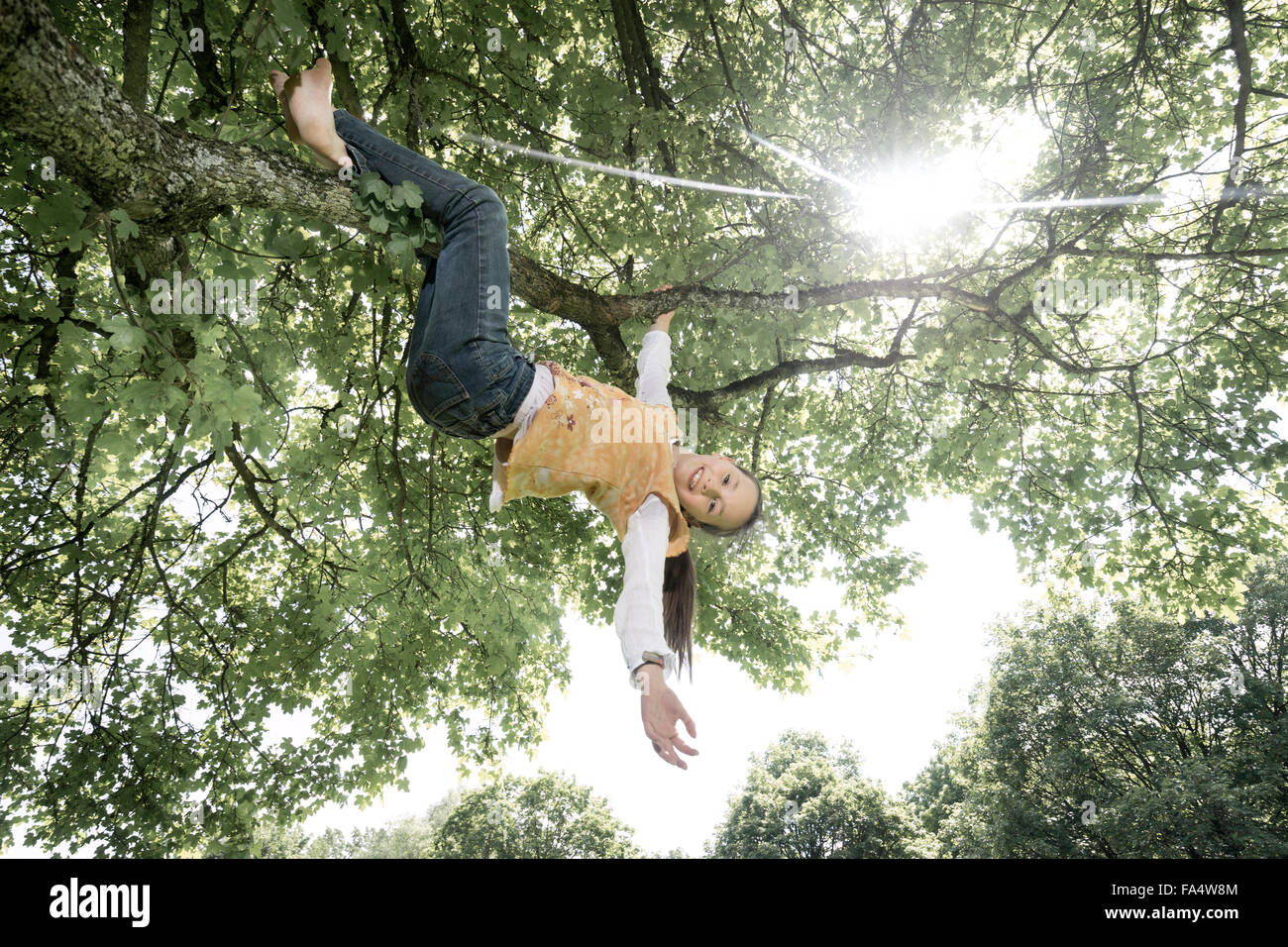 Girl hanging on tree et souriant, Munich, Bavière, Allemagne Banque D'Images