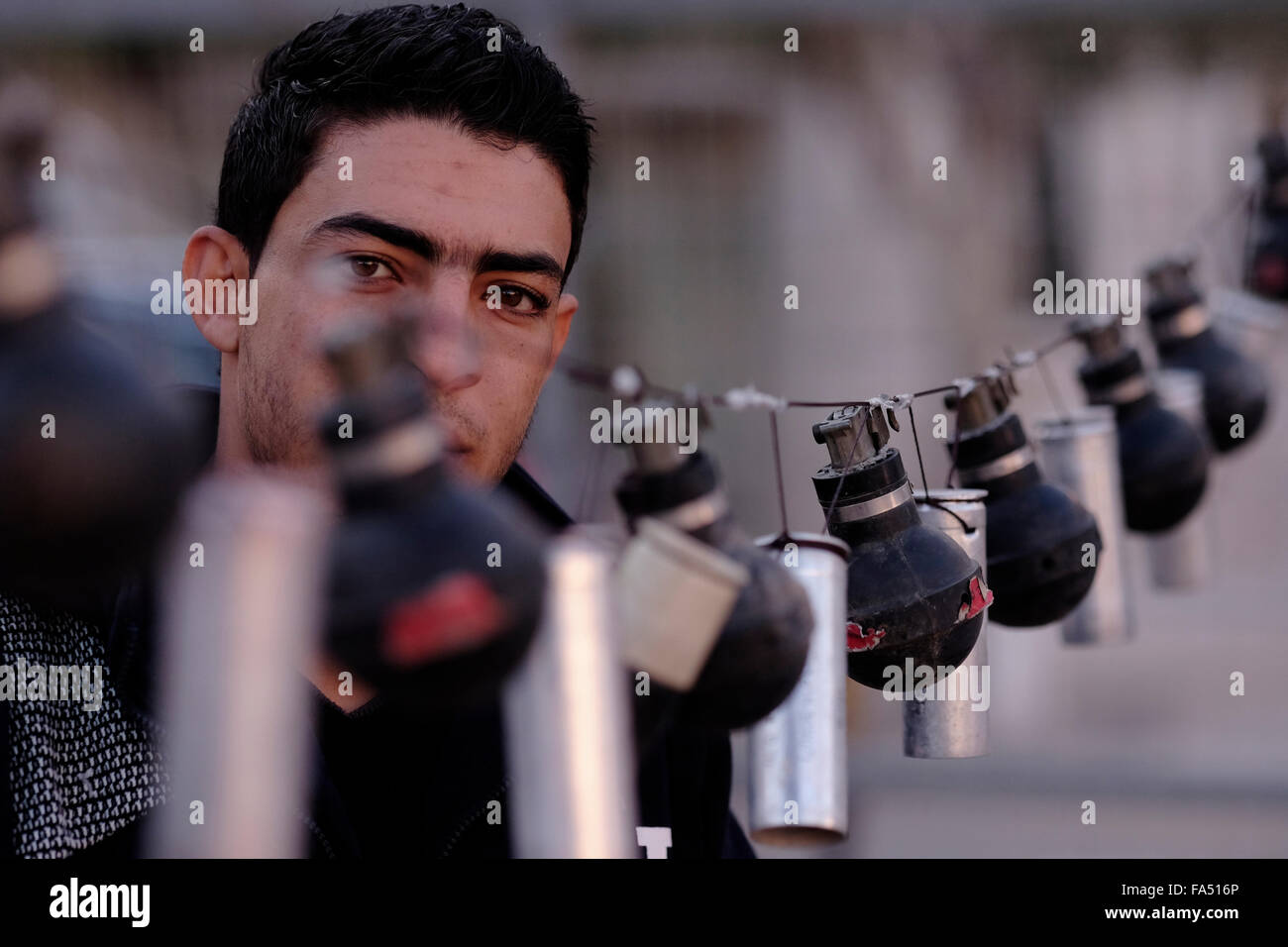 Un palestinien regarde à travers les restes pendus de bombes lacrymogènes et de grenades lacrymogènes utilisées par les forces israéliennes lors d'affrontements avec les Palestiniens en Cisjordanie Banque D'Images