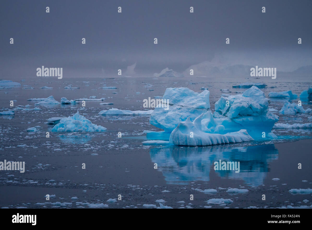 Beau et bien fait sur les icebergs un calme océan Antarctique, compensation de façon percutante contre l'moody sky, l'Antarctique. Banque D'Images
