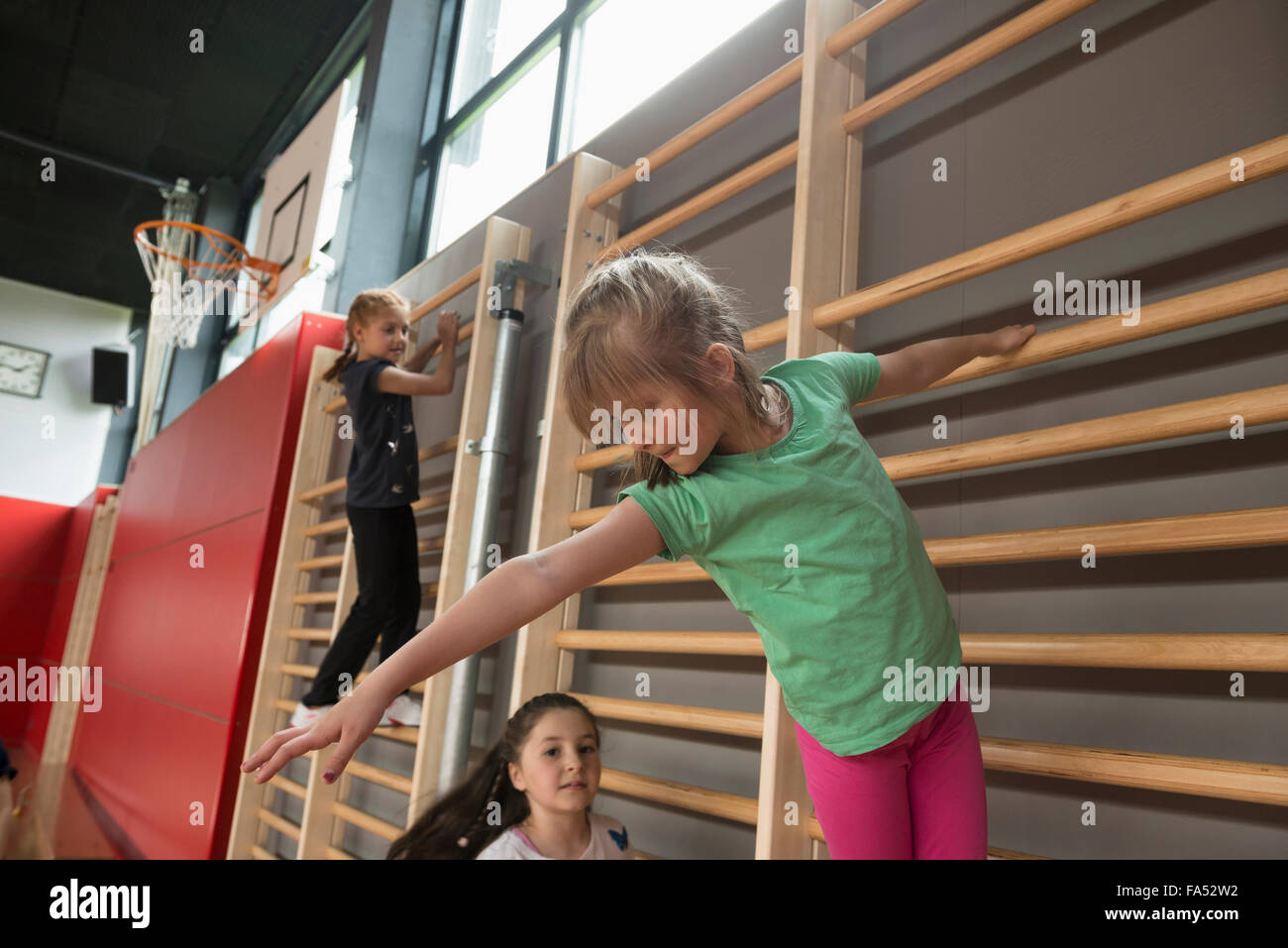 Trois jeunes filles exerçant sur le mur de bars dans grande salle de sport, Munich, Bavière, Allemagne Banque D'Images