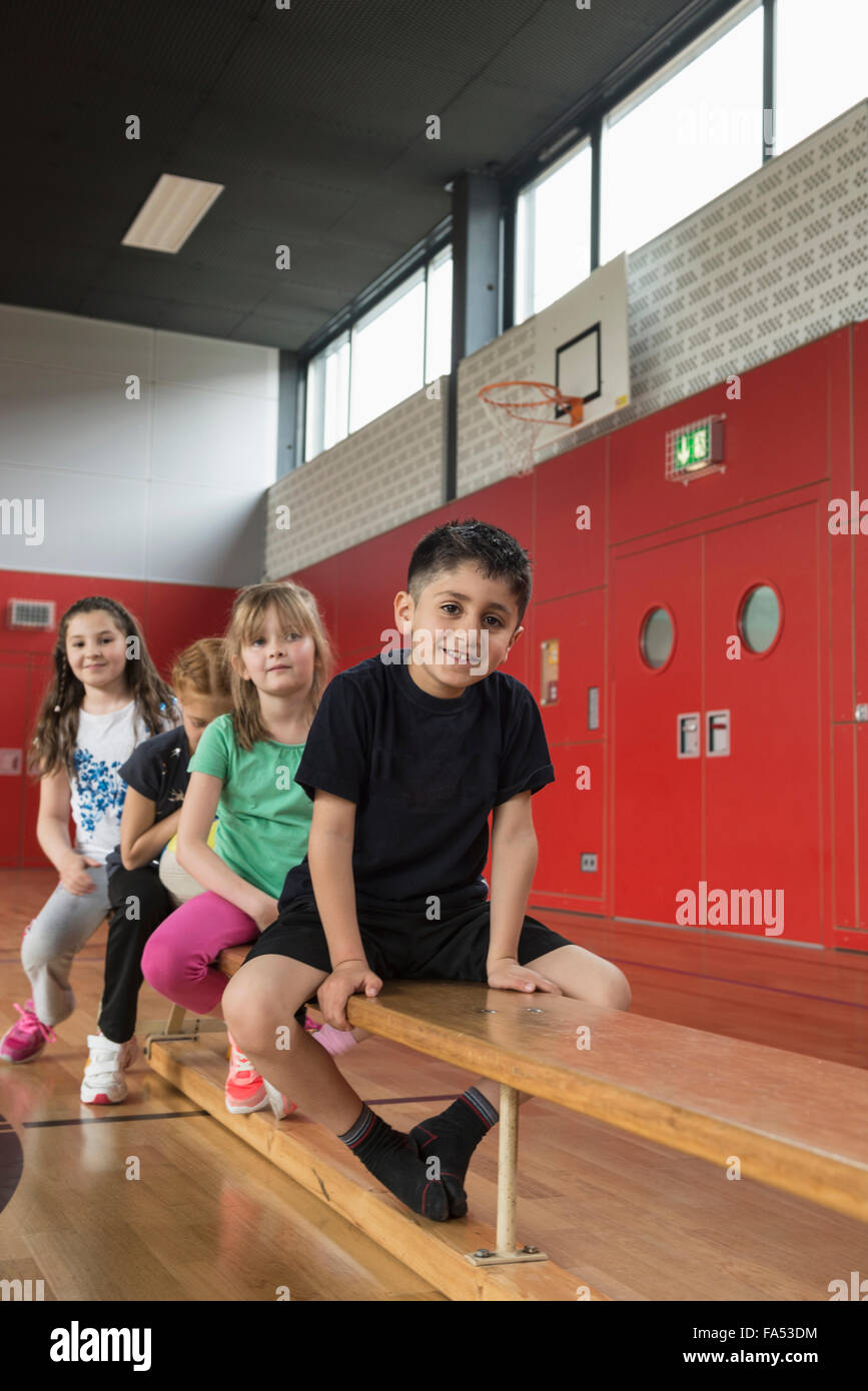 Les enfants assis sur un banc dans la salle de sport, Bavaria, Munich, Allemagne Banque D'Images