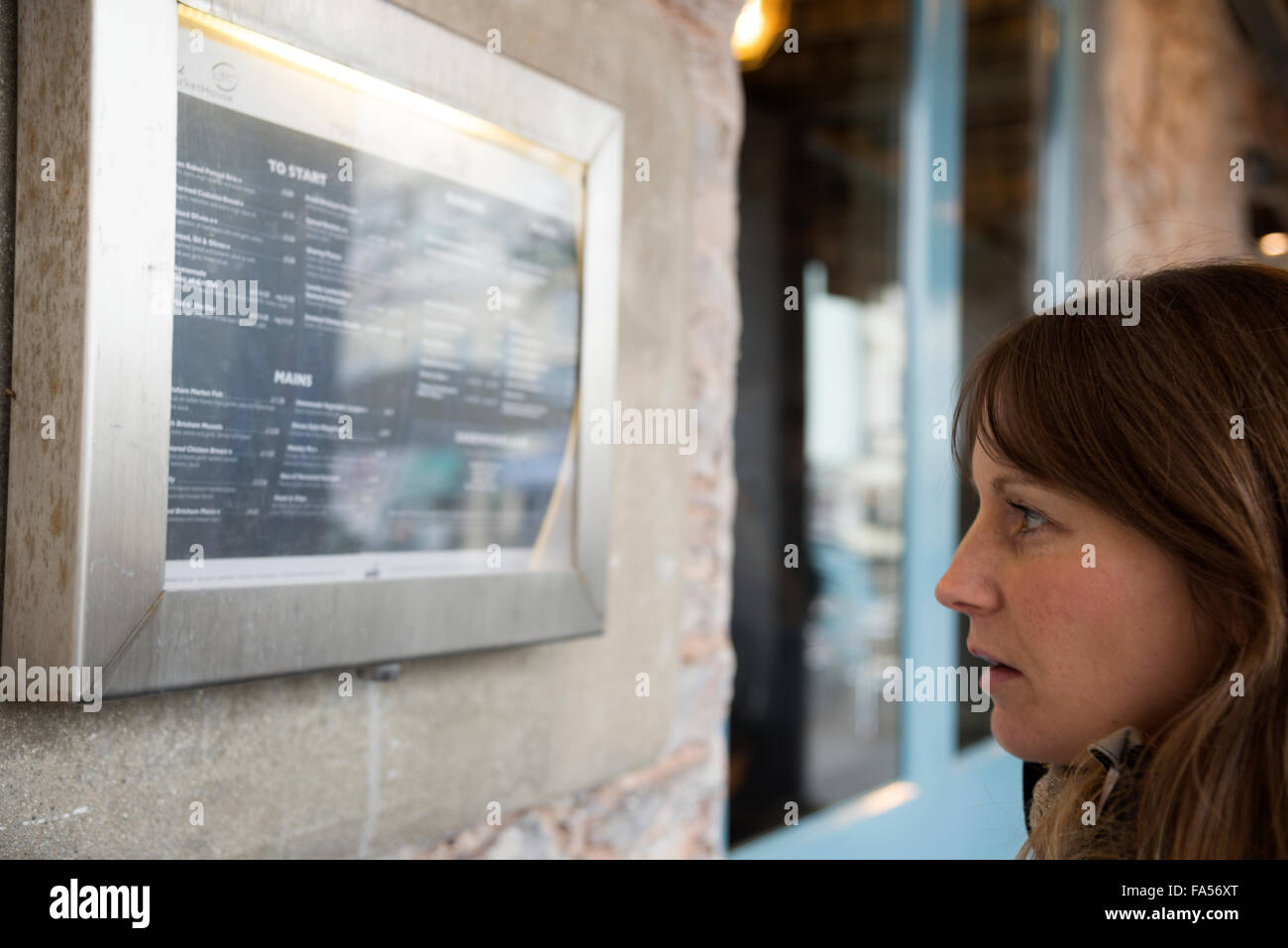 Une femme regarde un restaurant menu avec dégoût Banque D'Images