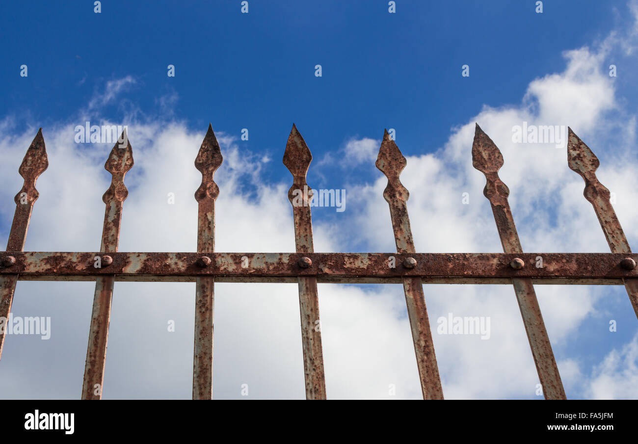 Détails d'une clôture rouillée, décorées avec des fers et du ciel et nuages dans l'arrière-plan. Banque D'Images