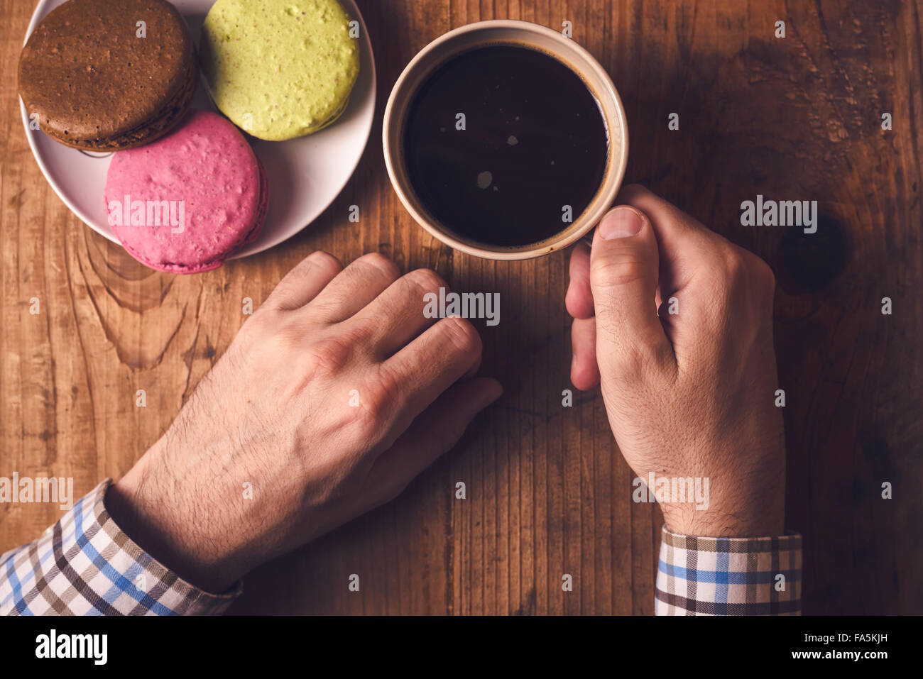 Café et biscuits macaron, homme hand holding cup avec boisson chaude, vue d'en haut, aux couleurs rétro Banque D'Images