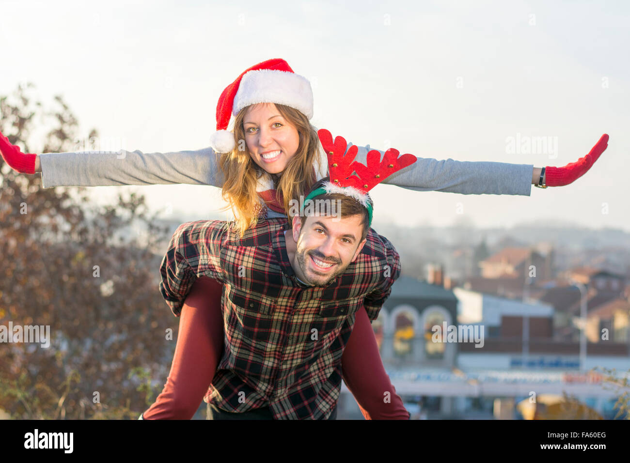 Couple in love piggyback équitation en plein air avec des chapeaux de Noël Banque D'Images