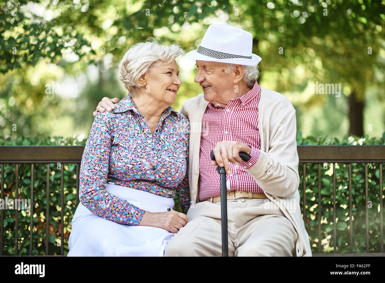 Les aînés heureux assis sur un banc dans le parc et profiter de la journée d'été Banque D'Images