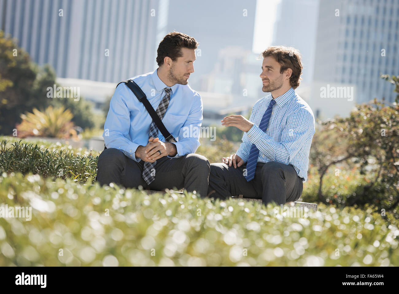 Deux hommes en chemises et cravates dans un parc de la ville. Banque D'Images