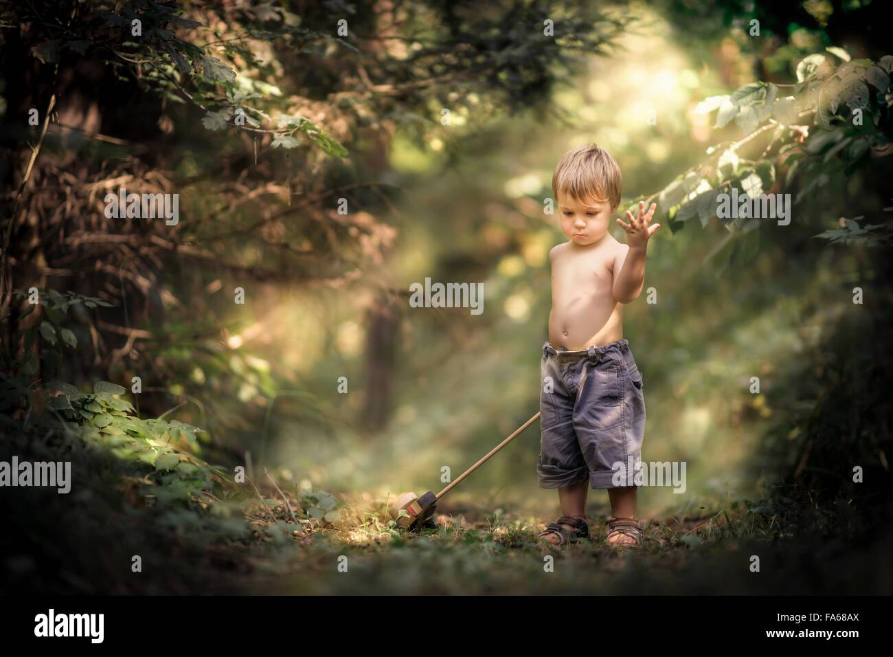 Boy standing in forest with toy Banque D'Images