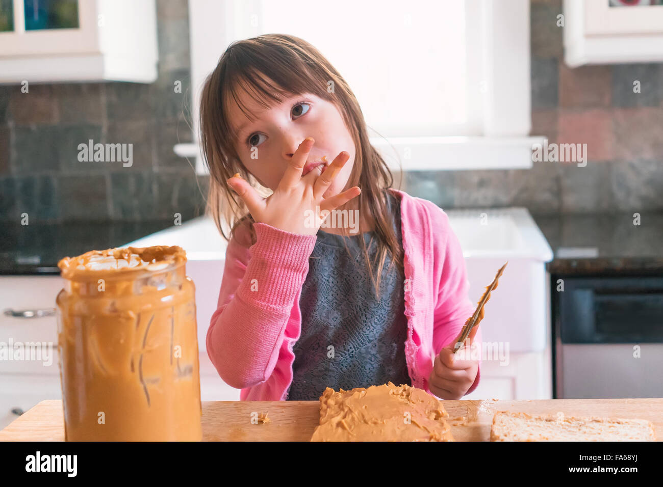 Girl making sandwich au beurre d'arachide, de lécher les doigts Banque D'Images