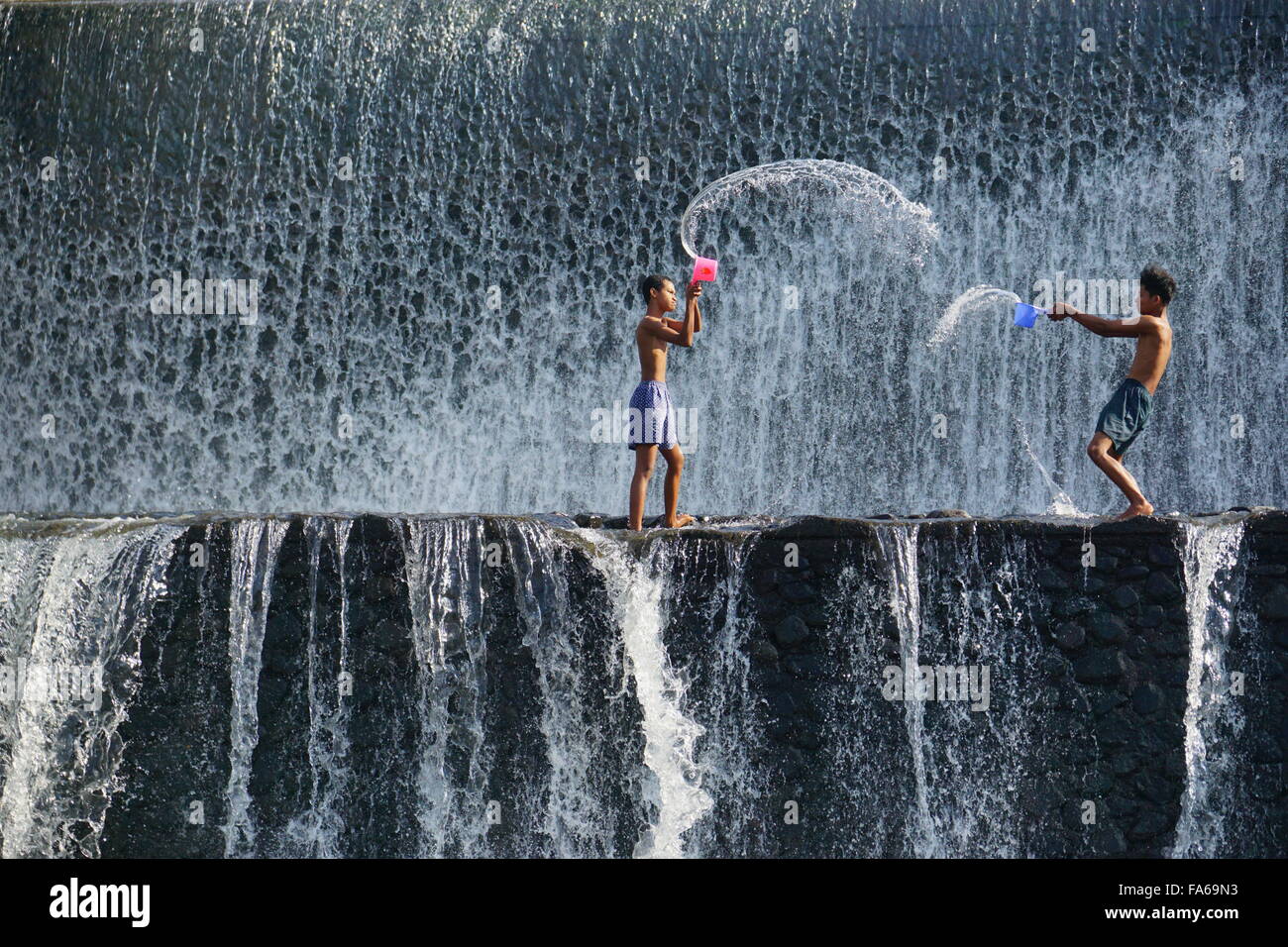 Deux garçons jetant de l'eau à l'autre, Tukad Unda Barrage, Bali, Indonésie Banque D'Images