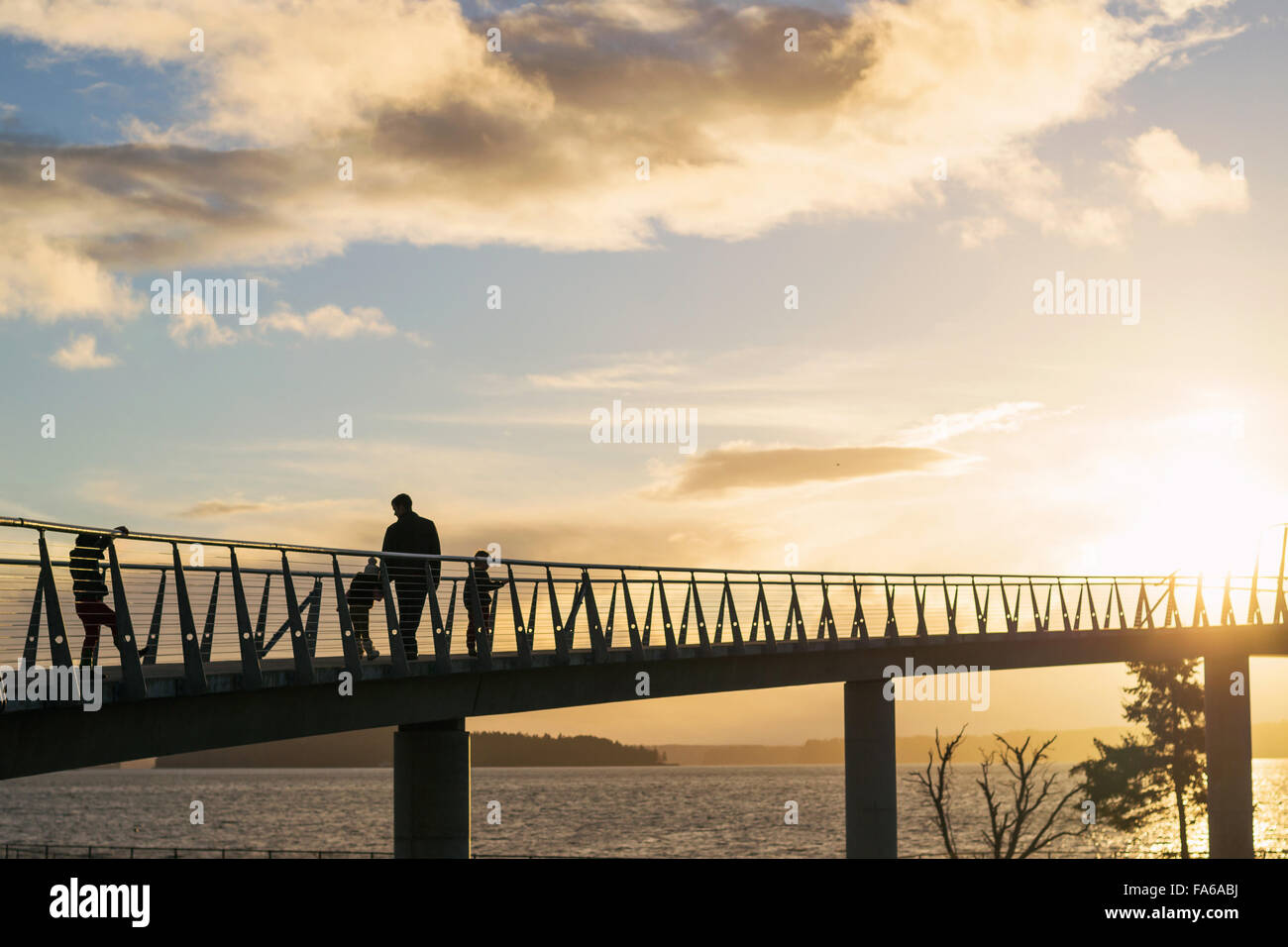 Silhouette of family walking over bridge au coucher du soleil Banque D'Images