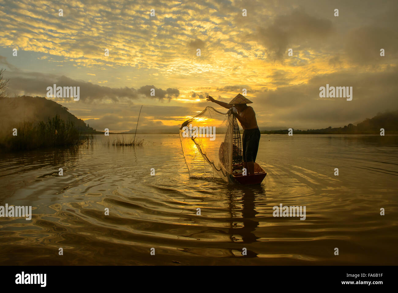 Silhouette d'un homme lançant filet de pêche, le lac de Bangpra, Thaïlande Banque D'Images