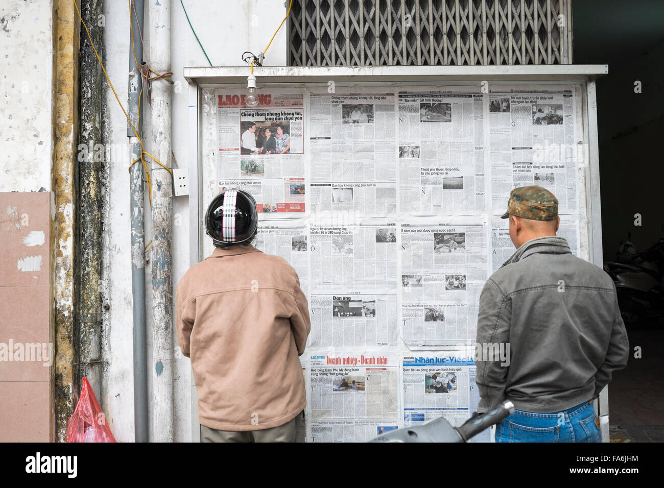 Les hommes lire les journaux sur un affichage à Phnom Penh , Cambodge Banque D'Images