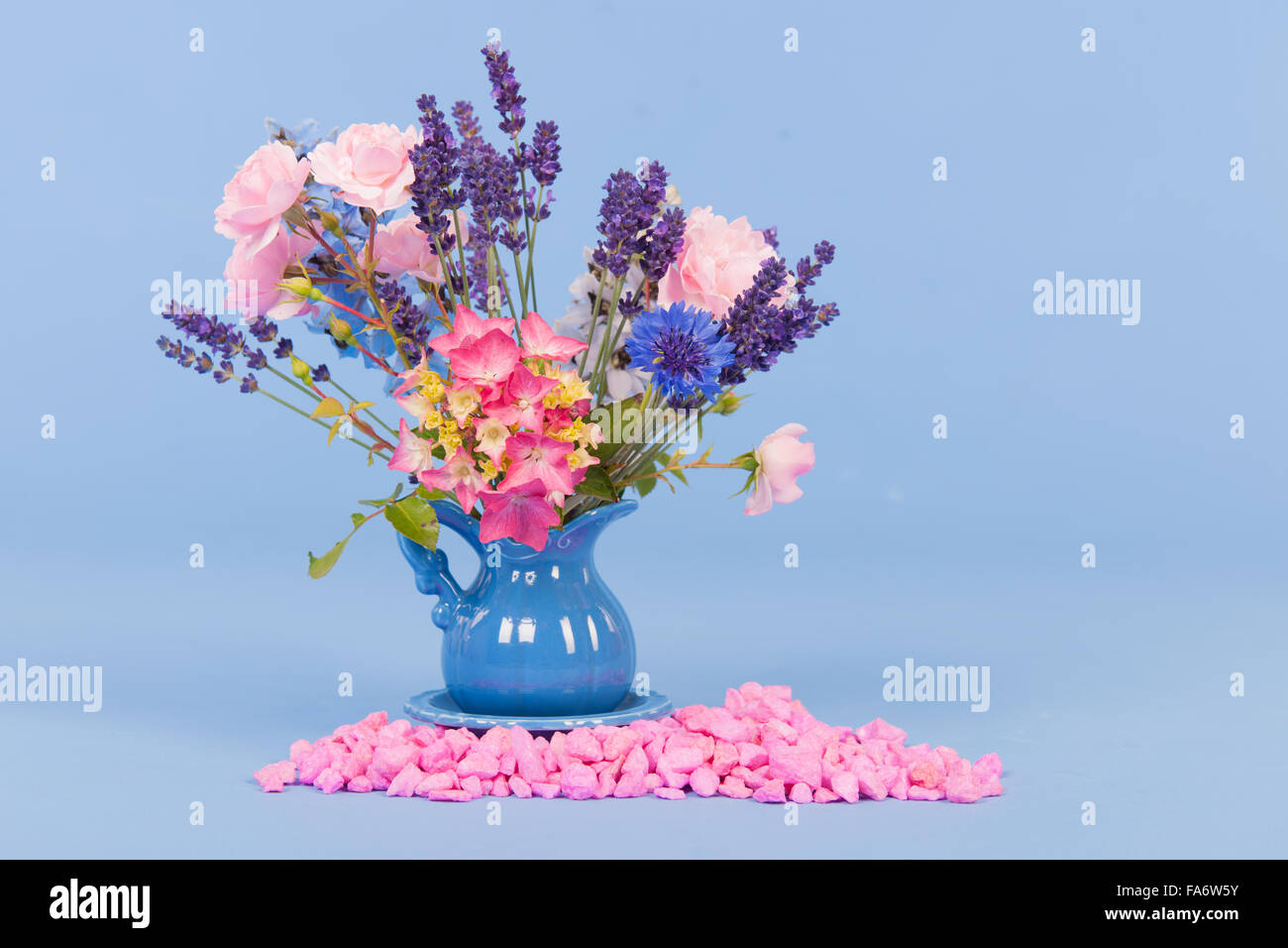 Bouquet dans un vase de fleurs colorées sur fond bleu Banque D'Images