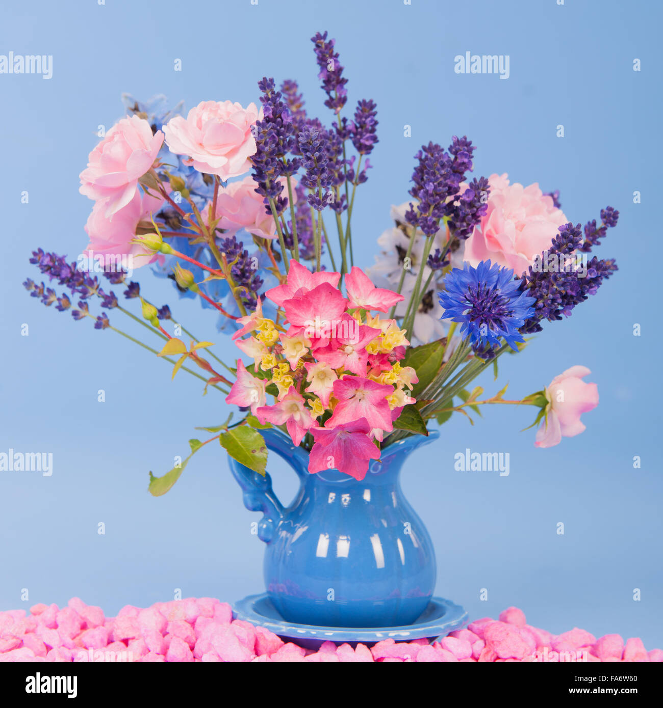 Bouquet dans un vase de fleurs colorées sur fond bleu Banque D'Images