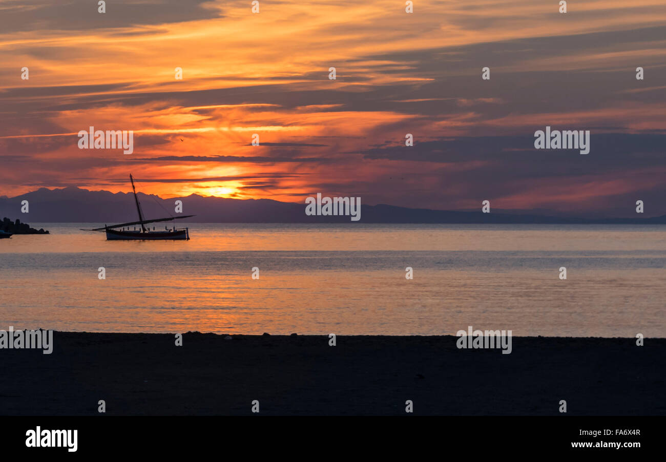 Coucher du soleil à Sestri Levante, Ligurie, Italie. Nuageux lumineux orange ciel et mer avec un voilier ancré. Banque D'Images