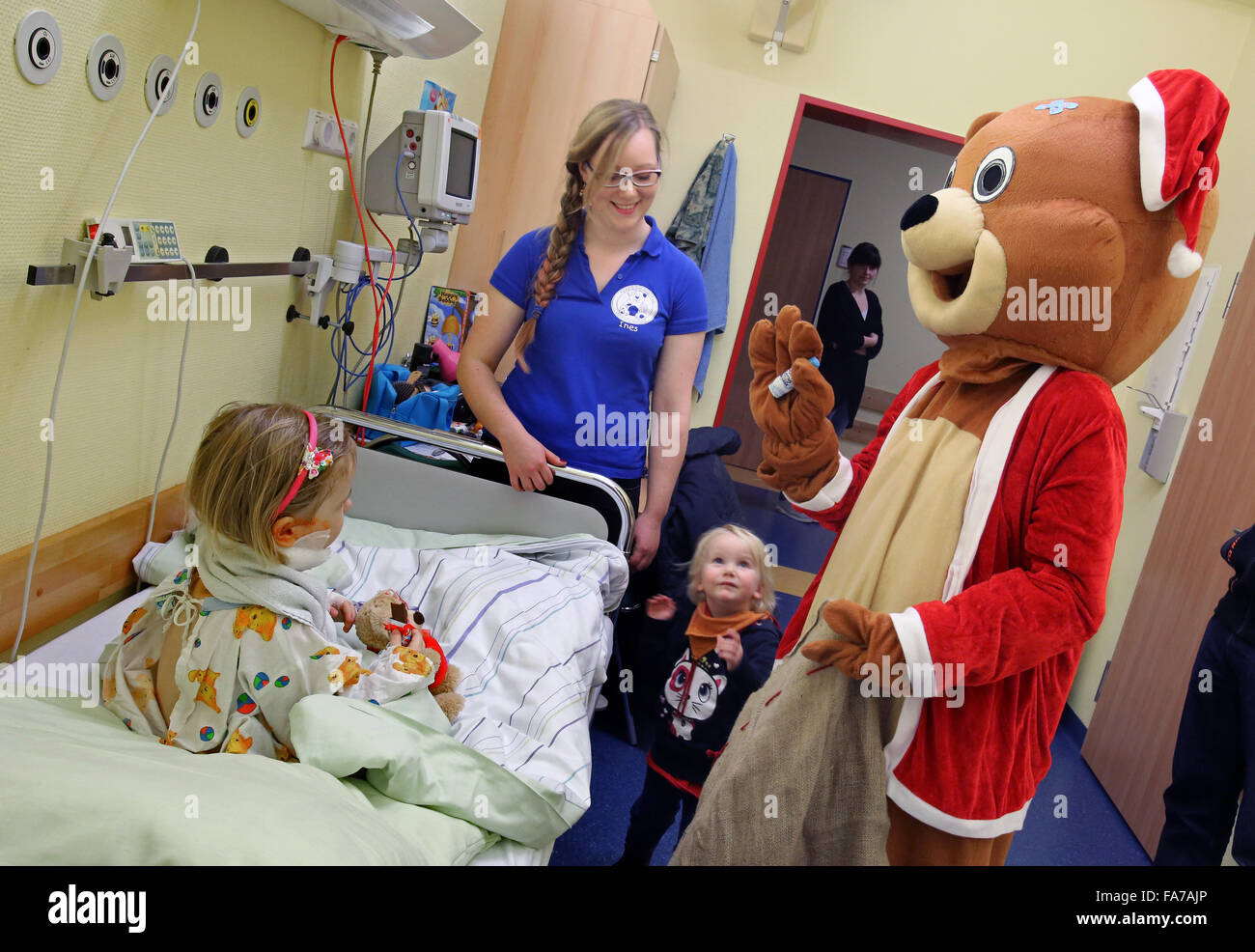 Rostock, Allemagne. Dec 22, 2015. Le Père Noël de l'hôpital de l'Ourson", accompagnée par Ines Angerer (2-L) qui campe un médecin principal, visites trois ans Finya (L) qui doit rester à l'hôpital pour Noël à la suite d'une chirurgie dans le service de chirurgie pédiatrique de l'hôpital universitaire de Rostock, Allemagne, le 22 décembre 2015. Peu de patients sont sortis de l'hôpital chaque fois que possible, mais ceux qui doivent rester à l'hôpital seront toujours voir le Père Noël. Photo : BERND WUESTNECK/dpa/Alamy Live News Banque D'Images