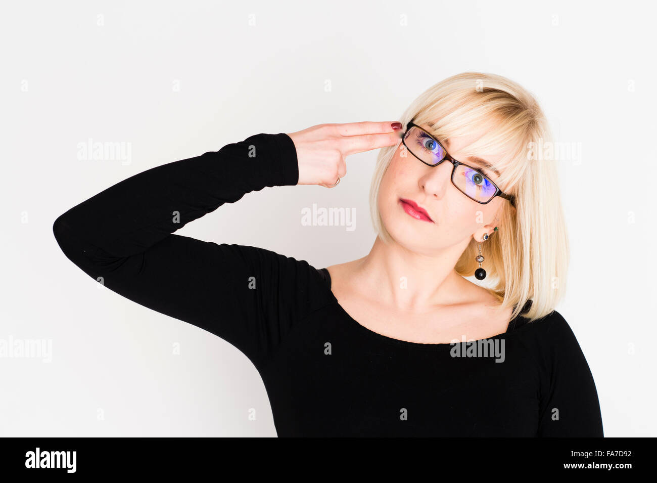 Une jeune femme aux cheveux blonds blonds slim girl, UK, porter des lunettes de tir elle-même la tête avec ses doigts en forme de pistolet factice Banque D'Images