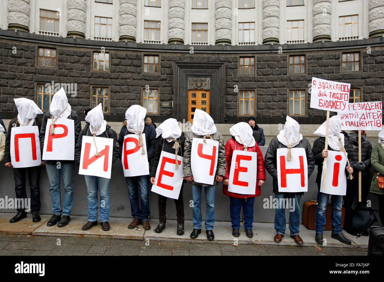 Kiev, Ukraine. Dec 23, 2015. Les activistes ukrainiens qui sont victimes du VIH SIDA et l'hépatite se tenir avec des sacs sur la tête et le noeud coulant autour du cou comme un symbole que le budget pour 2016 à une déficience et les condamne à la mort, et tenir les lettres pour former un mot 'Doomed', devant le Conseil des ministres.La demande des manifestants pour fournir les soins dont ils ont besoin et de budget pour 2016 pour le traitement des malades en phase critique d'Ukrainiens. Credit : Vasyl Shevchenko/Pacific Press/Alamy Live News Banque D'Images