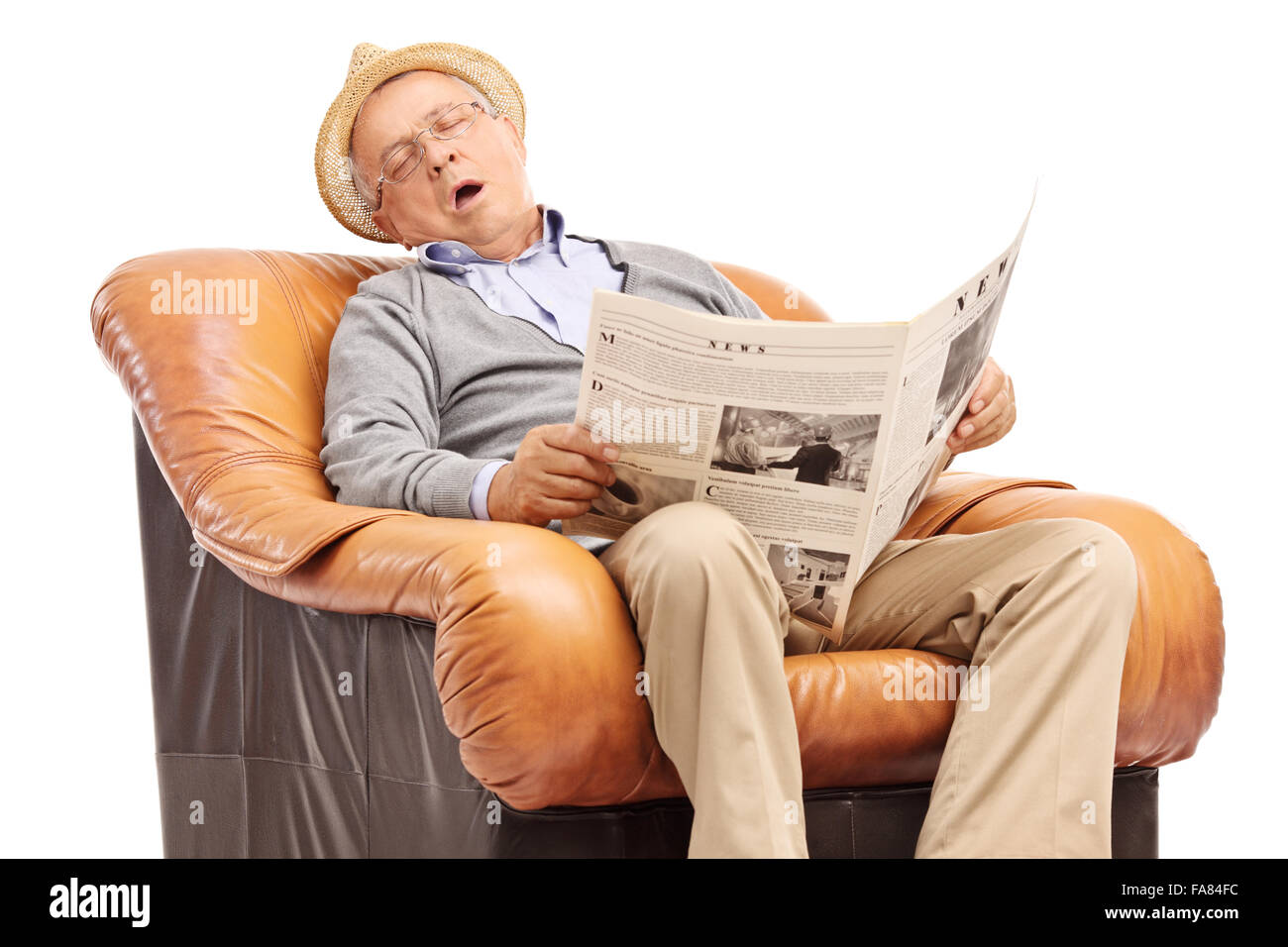 Studio shot of a senior man dormir sur un fauteuil et tenant un journal dans ses mains isolé sur fond blanc Banque D'Images