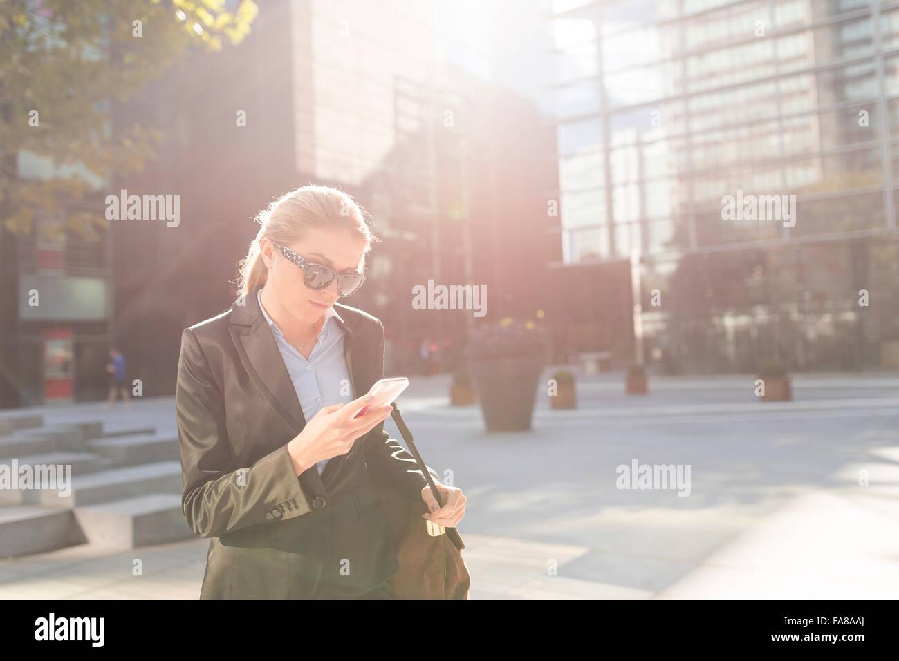 Young businesswoman hors bureau ville lecture textes smartphone Banque D'Images