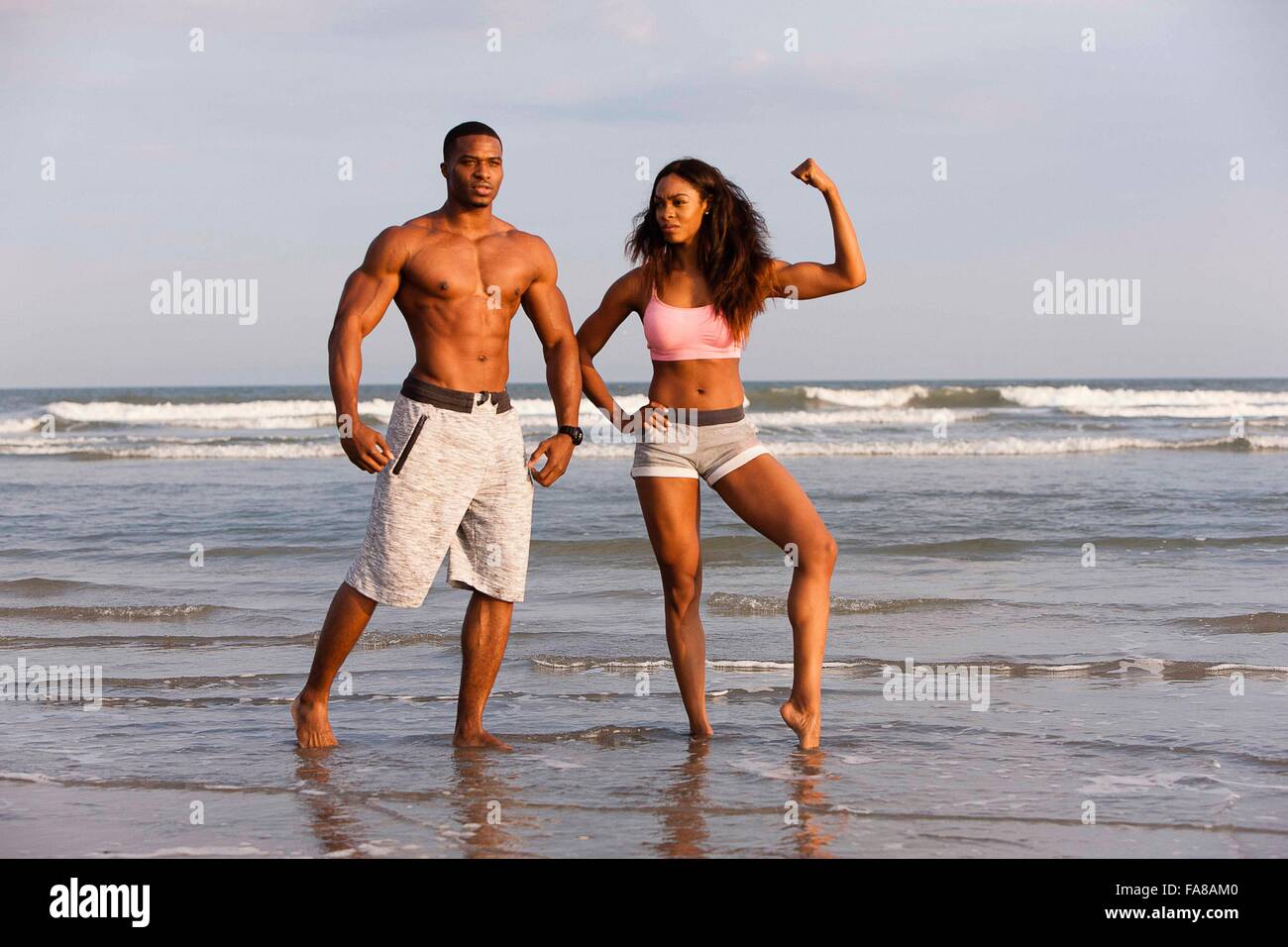 Couple on beach, flexing muscles, posing Banque D'Images