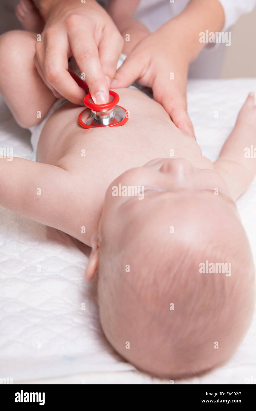 Pédiatre en sarrau blanc examine trois mois bébé garçon à l'aide d'un stéthoscope Banque D'Images