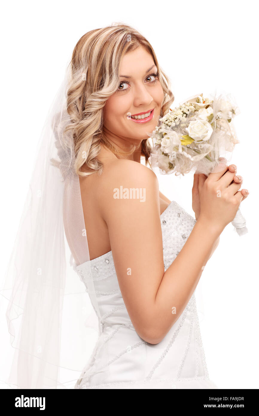Shot verticale d'une jeune mariée dans une robe de mariée blanche tenant un bouquet de fleurs mariage et regardant la caméra Banque D'Images