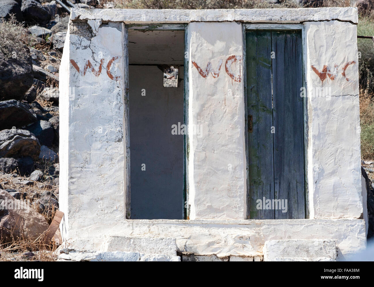 Les Cyclades, Santorin. Bloc sanitaire de base rurales blancs avec deux portes, l'une ouverte, d'autres avec peeling patiné porte bleue, pour les WC, toilettes publiques. Banque D'Images