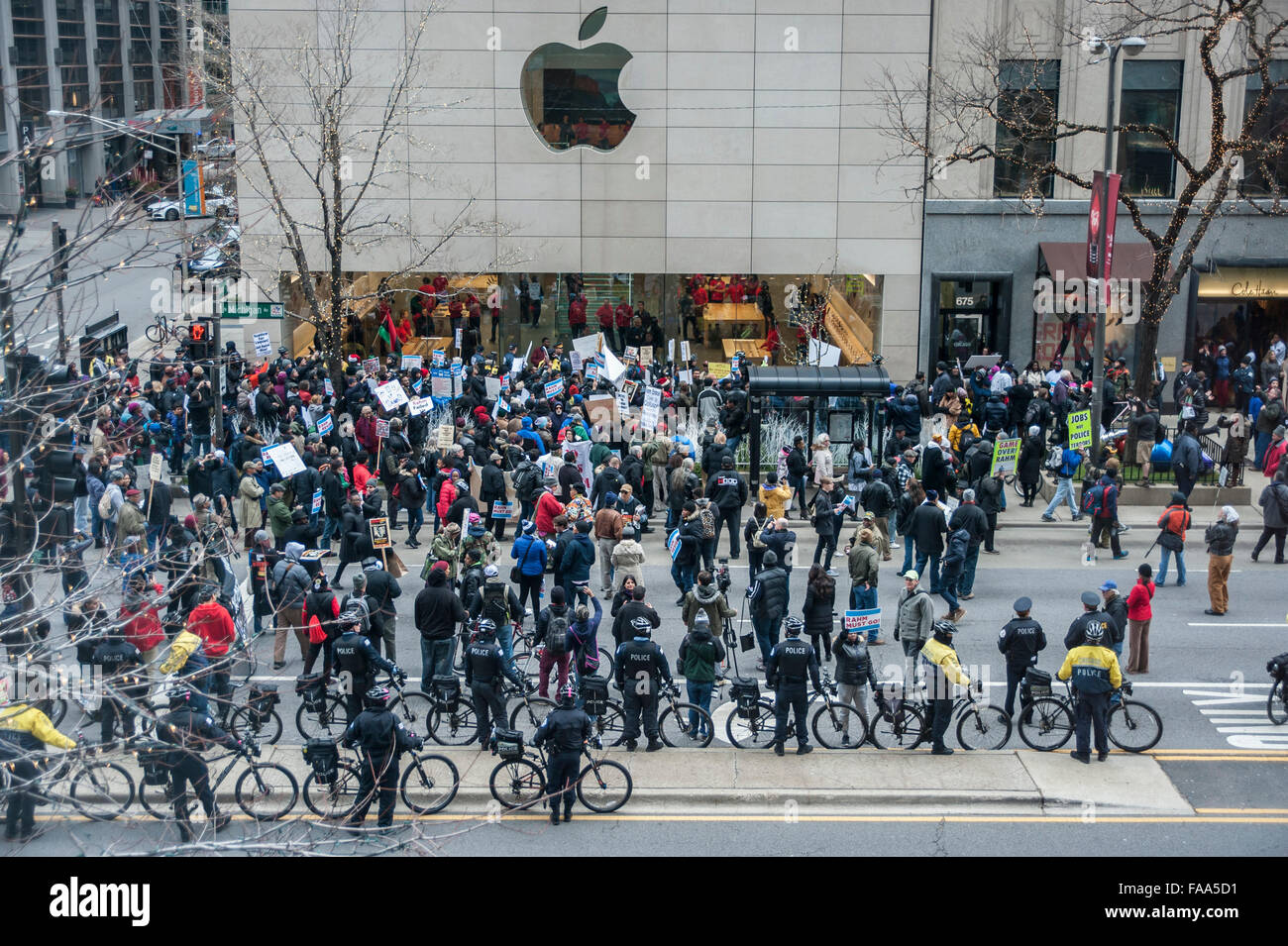 Chicago, USA. 24 décembre 2015. Des centaines de personnes se rassemblent à mars vers le bas de l'Avenue Michigan Magnificent Mile' commerçant sur la veille de Noël pour protester contre les allégations de camouflage de police liés à la mort d'Laquand McDonald par un policier de Chicago. Entouré de membres de la force de police de Chicago, des manifestants scandaient "16 coups et une dissimulation," et appelant à la maire de Chicago Rahm Emanuel de démissionner, sur ce qui a été décrit comme 'Black Christmas'. Grands magasins ciblés des manifestations telles que l'Apple Store, sur la photo. Crédit : Stephen Chung / Alamy Live News Banque D'Images