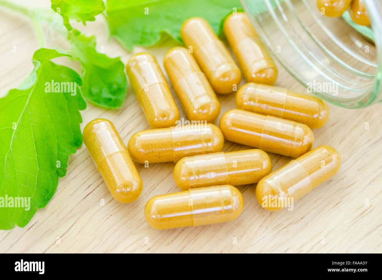 Capsules à base de plantes jaune avec vert feuille sur fond de bois. Banque D'Images