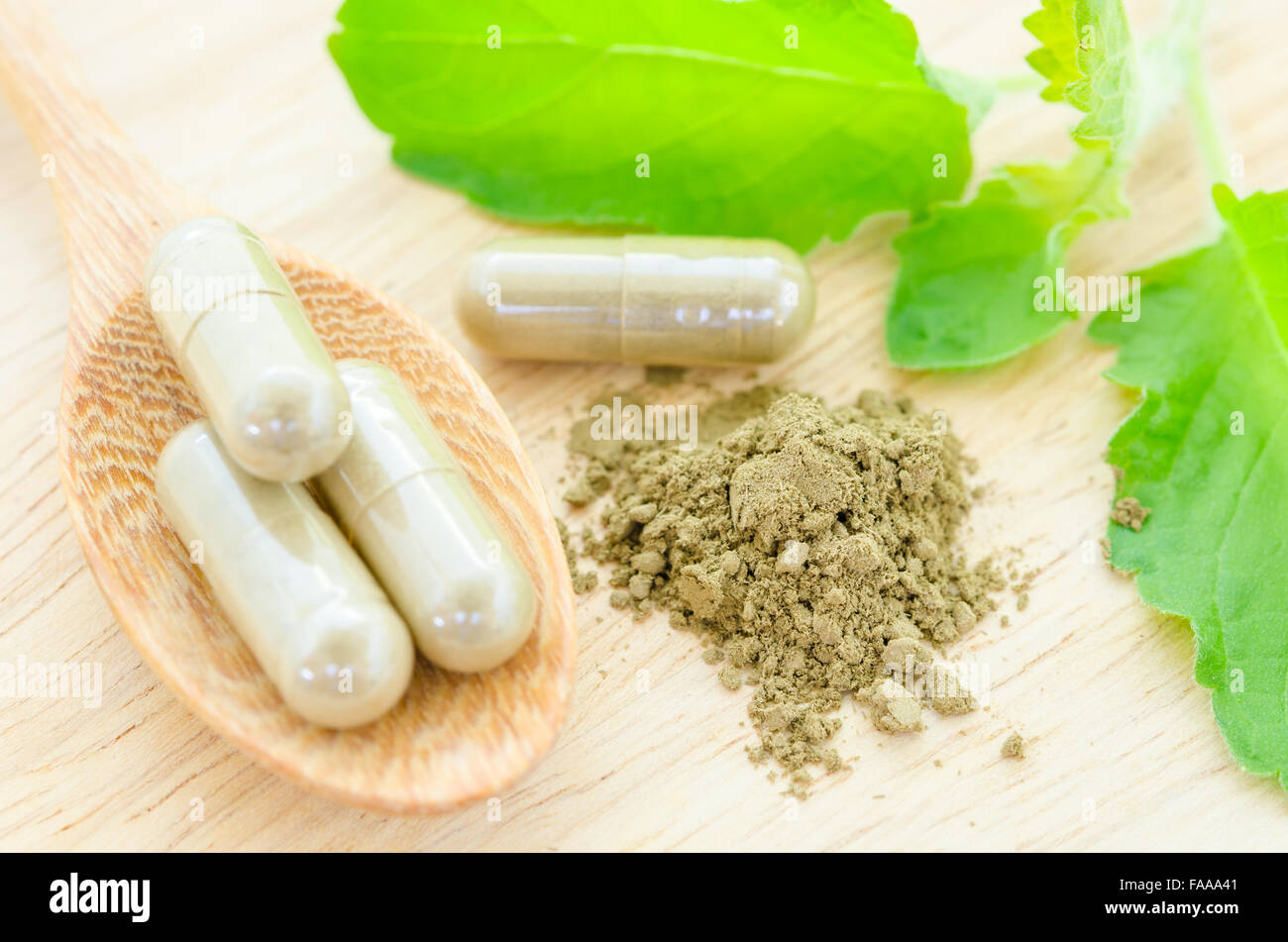 Phytothérapie en capsules avec feuille verte sur fond de bois. Banque D'Images