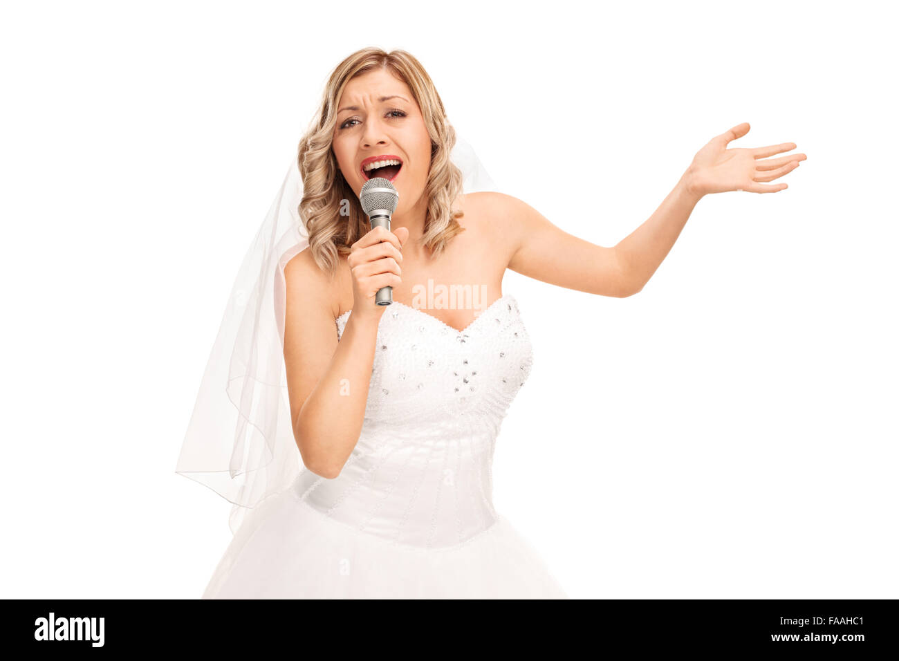 Jeune blonde bride dans une belle robe de mariée blanche en chantant dans un micro isolé sur fond blanc Banque D'Images