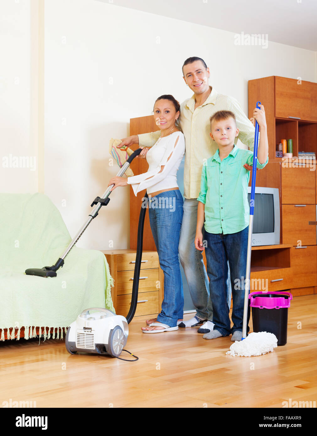 La famille ordinaire de trois avec le matériel de nettoyage dans la maison  Photo Stock - Alamy