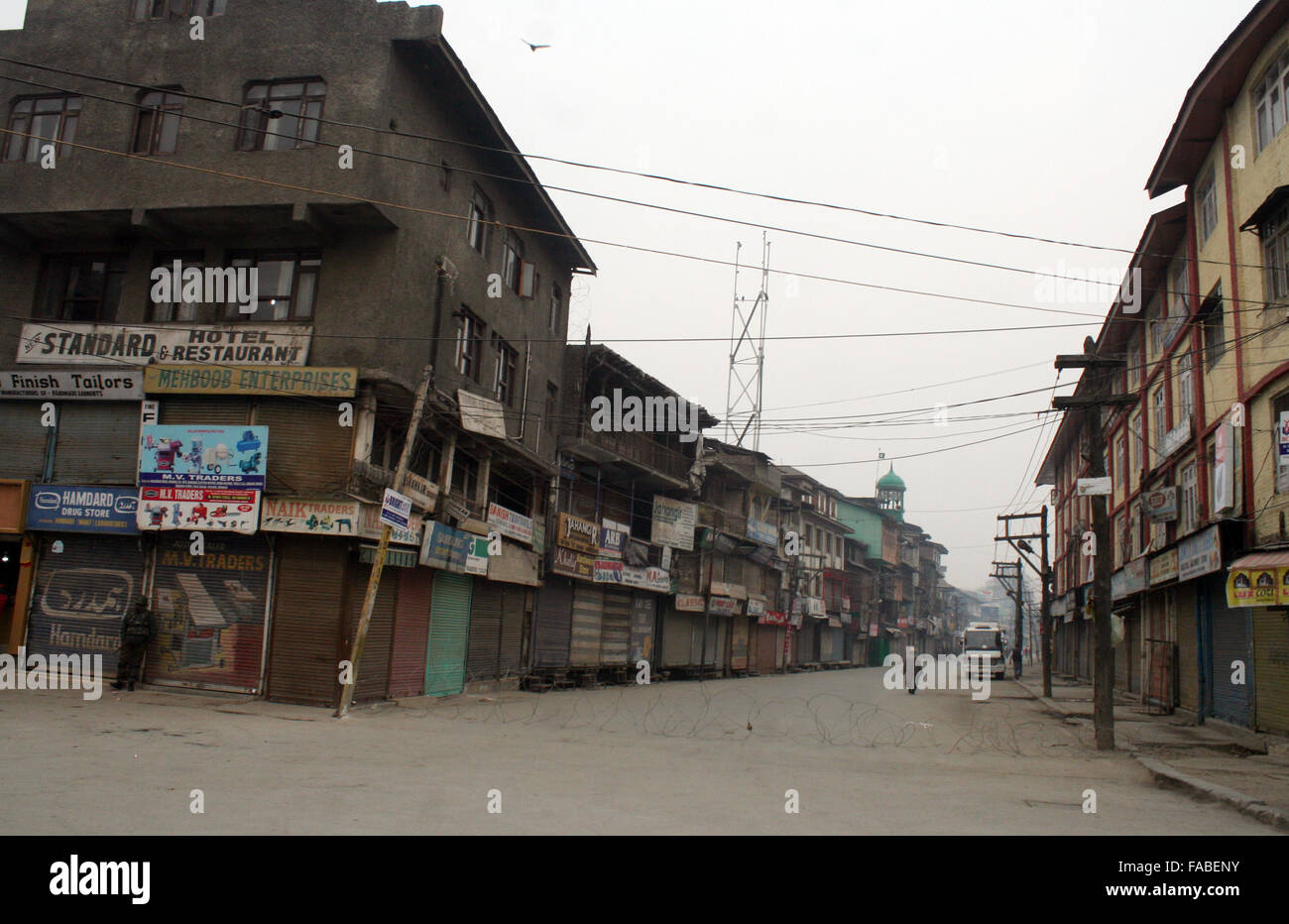 Srinagar, Cachemire indien : 26 Décembre, 2015. Les policiers indiens montent la garde devant les boutiques fermées pendant un arrêt arrêt .A L'appel a été donné par le leader séparatiste extrémiste Syed Ali Geelani pour protester contre des massacres par Village Commission de défense (VCC) membres. Trois personnes, dont une mère et son fils ont été tués dans deux incidents séparés par des membres VDC (un corps de volontaires civils armés par le gouvernement pour lutter contre les insurgés) dans la région de Jammu. Credit : Sofi Suhail/Alamy Live News Banque D'Images