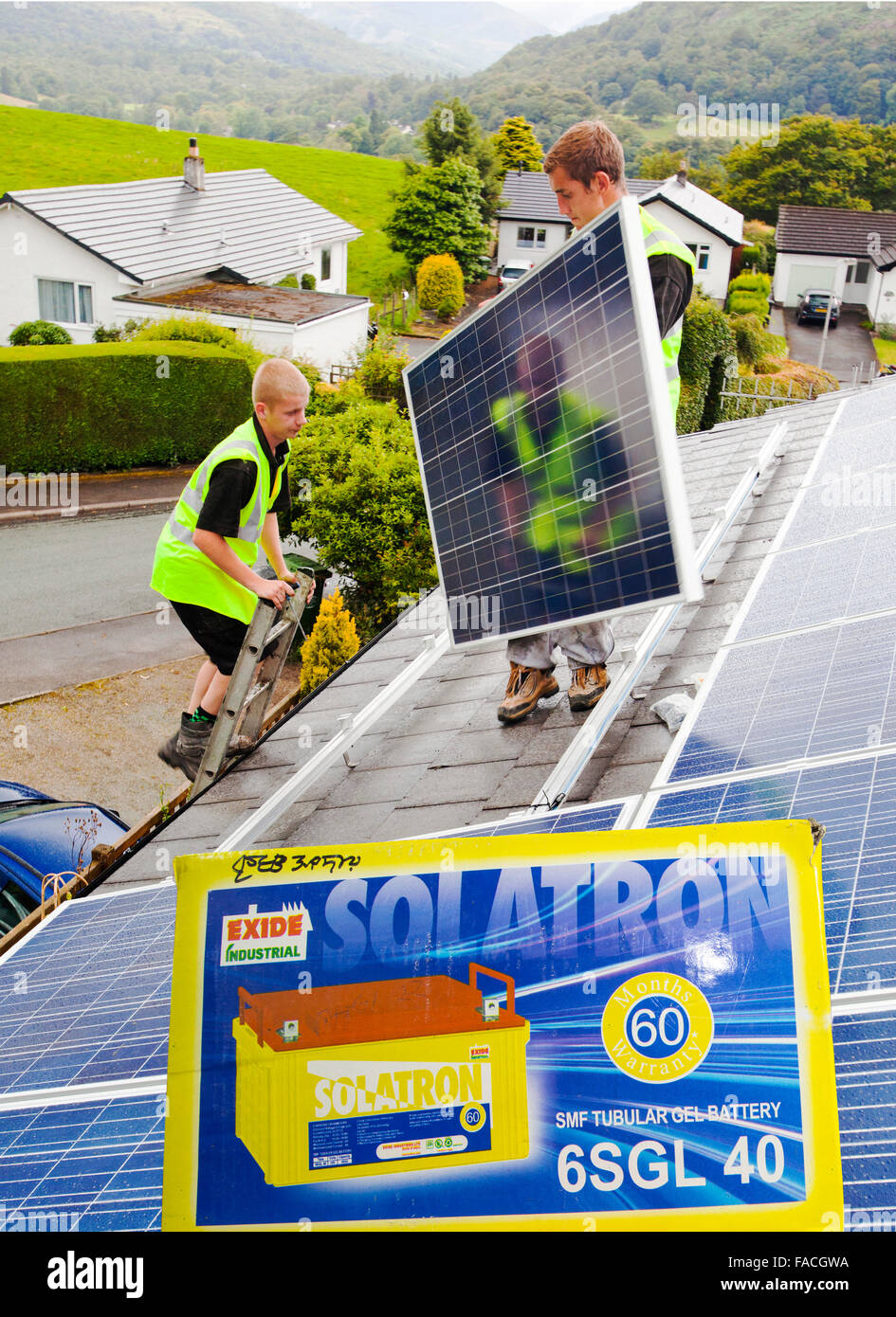Mise en place des techniciens de panneaux photovoltaïque sur le toit de ma maison à Ambleside, Cumbria. Bien que le Lake District est réputé pour son climat humide et nuageux, avec quelques 70 Ambleside pouces de pluie par an, ces panneaux produisent les trois quarts de mes besoins en électricité. Image composite avec une batterie solaire. Banque D'Images