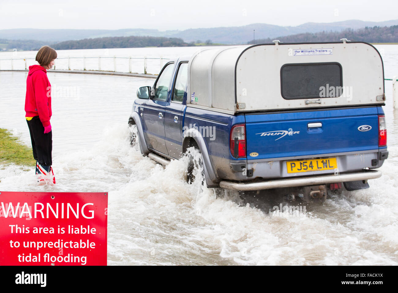Un automobiliste se rend dans les eaux d'inondation sur la route à l'estuaire de Kent sur Storth en Cumbria, UK, au cours de la tempête de janvier 2014 Banque D'Images