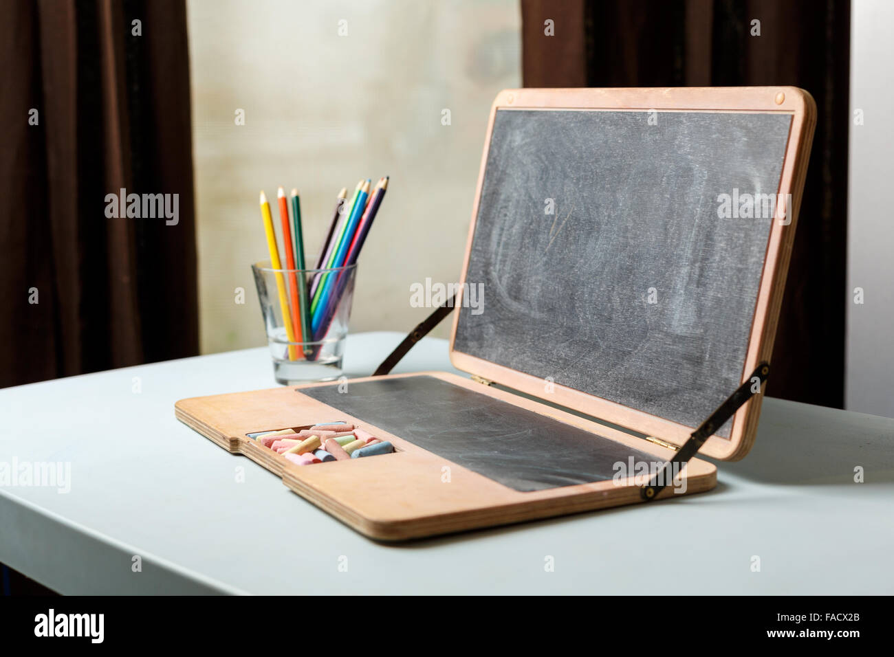 Dans un tableau sous forme d'un ordinateur portable avec les craies et les crayons de couleur dans un verre Banque D'Images