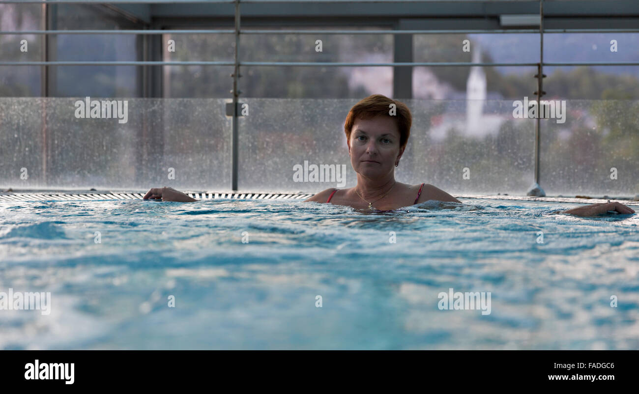 Middle aged woman relaxing in jacuzzi avec grande fenêtre Banque D'Images