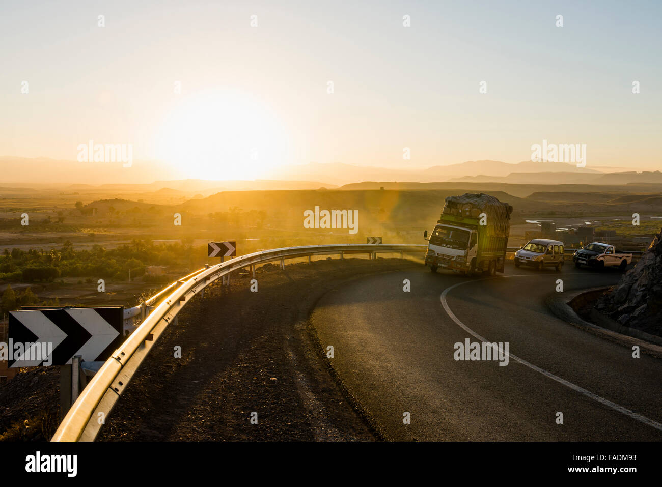 Camion chargé sur route sinueuse dans la vallée du Dadès au coucher du soleil, Ouarzazate, Maroc Banque D'Images