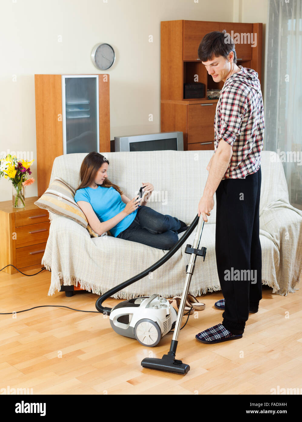 L'homme le nettoyage à l'aspirateur le plancher à la maison pendant plus de  repos femme canapé Photo Stock - Alamy