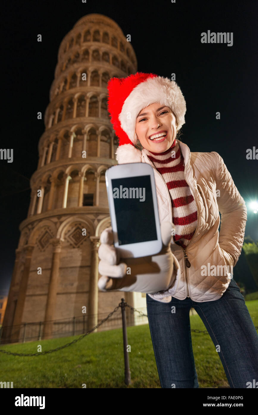L'emblématique de l'architecture italienne ajoute du style à la célébration de Noël. Happy young woman in Santa hat montrant téléphone mobile. Banque D'Images