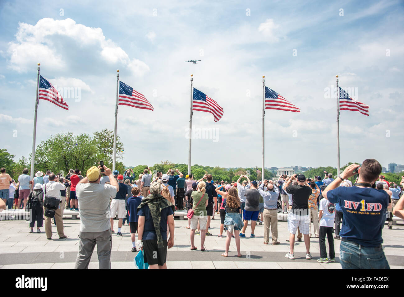 Les gens qui regardent les avions volent au-dessus des drapeaux américains. Banque D'Images