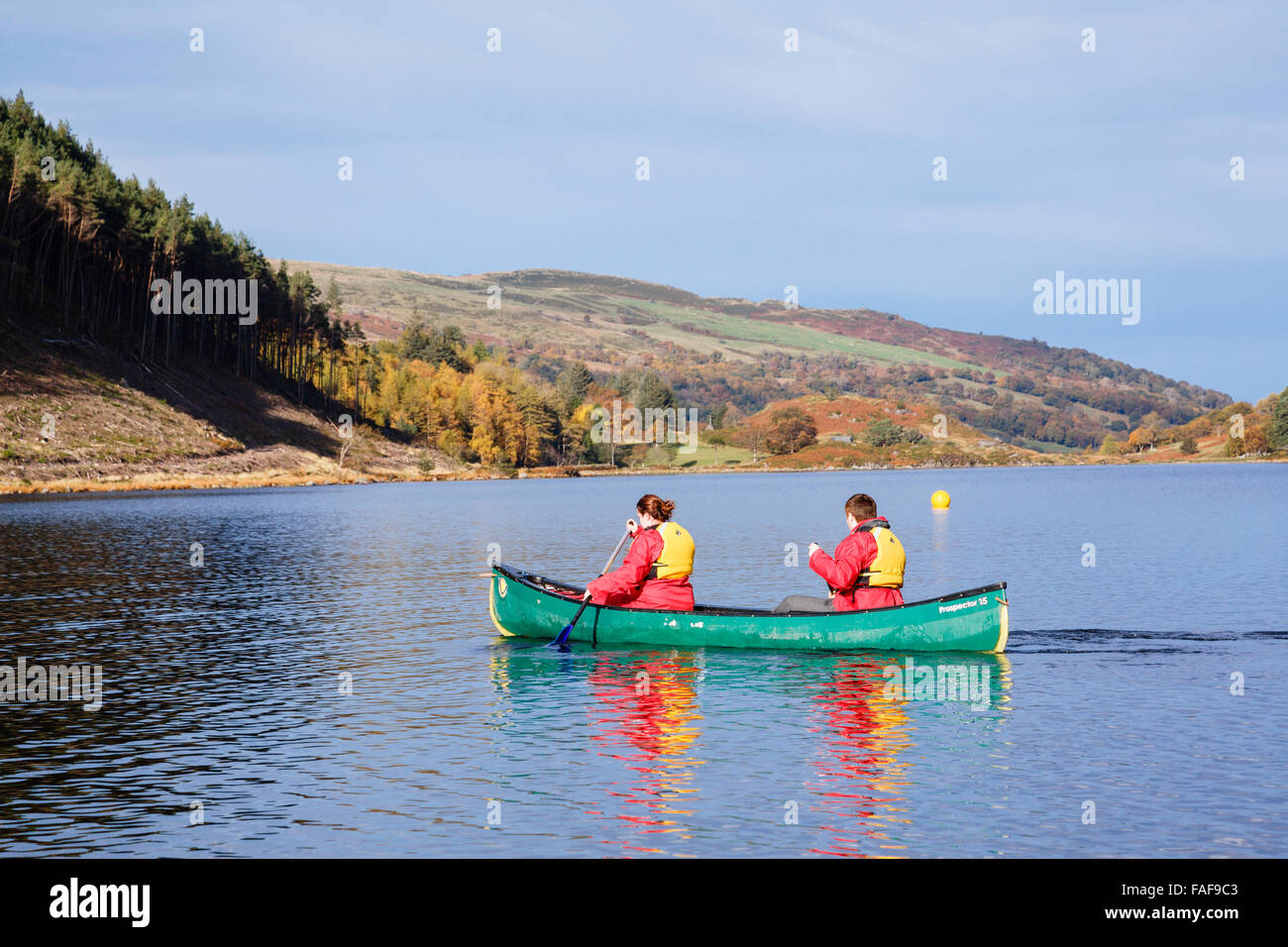 Deux jeunes gens portant des gilets de pagayer en canoë sur un Geirionydd Llyn lake sur une journée ensoleillée à l'automne dans le parc national de Snowdonia. Pays de Galles UK Banque D'Images
