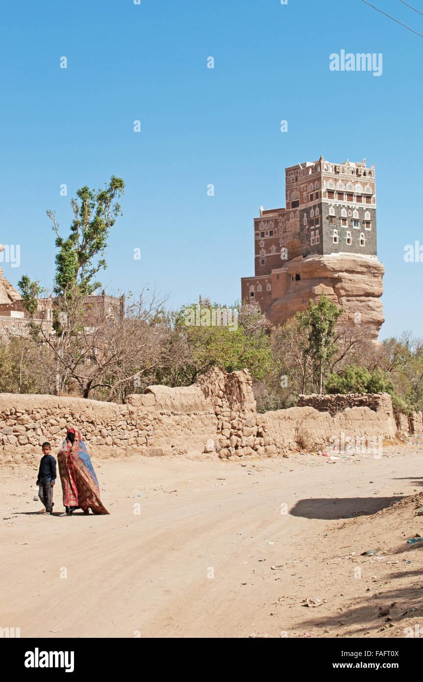 Une femme voilée et un enfant marcher près de Dar al-Hajar, Dar al Hajar, le Rock Palace, palais royal, symbole iconique du Yémen Banque D'Images