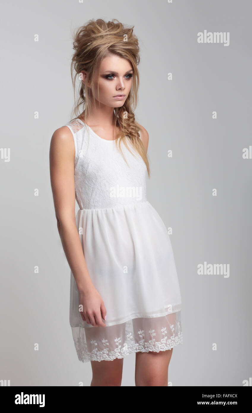 Belle jeune fille en robe blanche est sur un fond clair. Banque D'Images