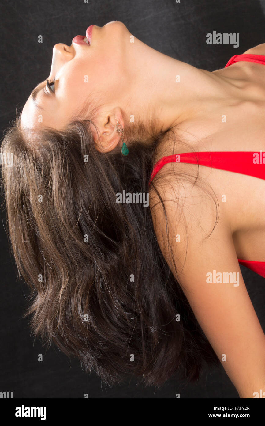 Tête et épaules image of young woman dancer, profile of dramatic back bend en robe rouge sur fond noir. Banque D'Images