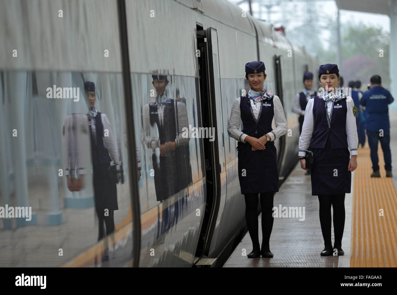 Haikou, province de Hainan en Chine. Dec 30, 2015. Pour les passagers à l'extérieur d'attente Steward un train à la gare de Haikou Haikou, capitale de la province de Hainan en Chine du Sud, 30 décembre 2015. Les 345 km de chemin de fer de l'ouest de l'anneau à Hainan a été mis en service le mercredi, complétant la première ligne de train à grande vitesse autour d'une île. Le tronçon ouest, conçu avec une vitesse de 200 km par heure, a 16 s'arrête dans six villes et comtés, reliant la capitale provinciale Haikou avec Sanya, un endroit touristique tropical. Credit : Zhao Yingquan/Xinhua/Alamy Live News Banque D'Images